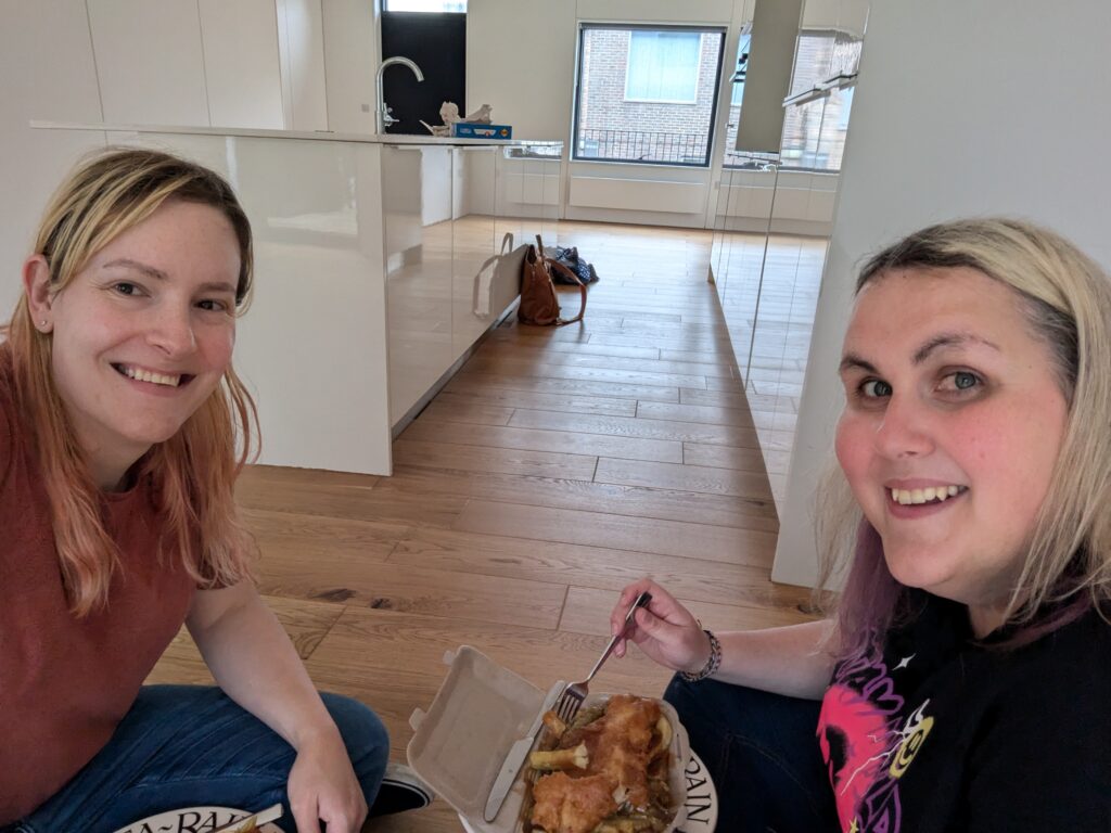 Chris and Meg sit on the floor of an empty property eating fish and chips.